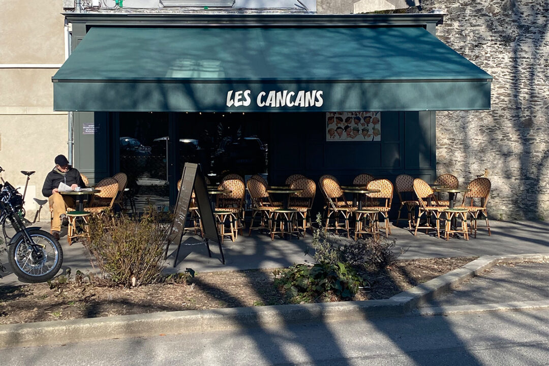 Store banne Madrid de 6x4 m en toile coloris SWITCH VERT U395 avec lambrequin lumineux en led blanc installé au bar Les Cancans à Nantes (44) par Espacio.